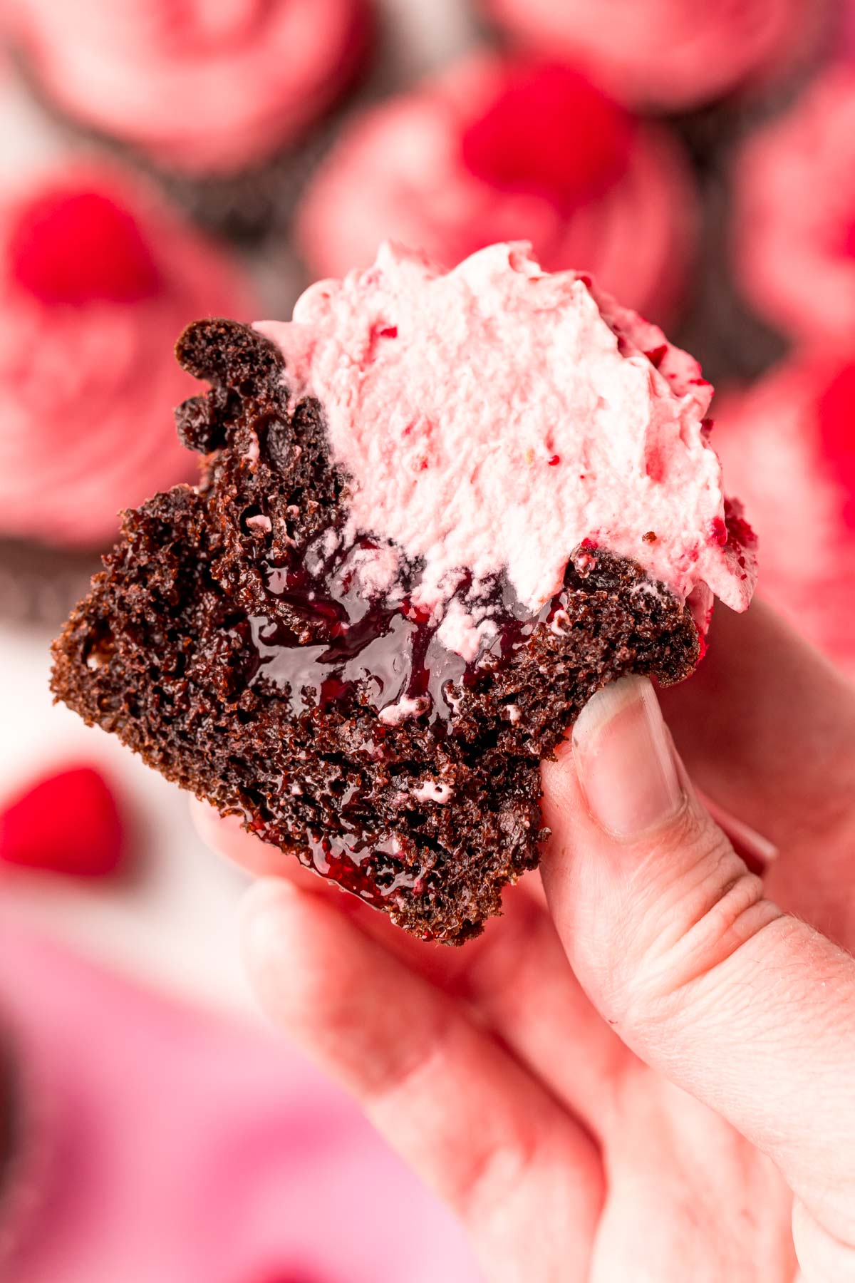 A chocolate raspberry cupcake that's been sliced in half to show the filling.