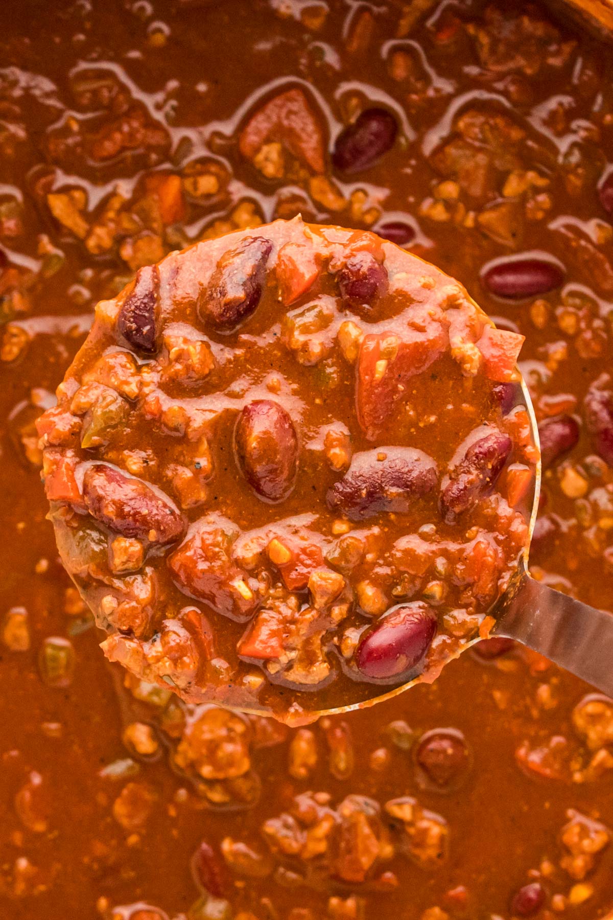 A ladle scooping turkey chili out of a pot.