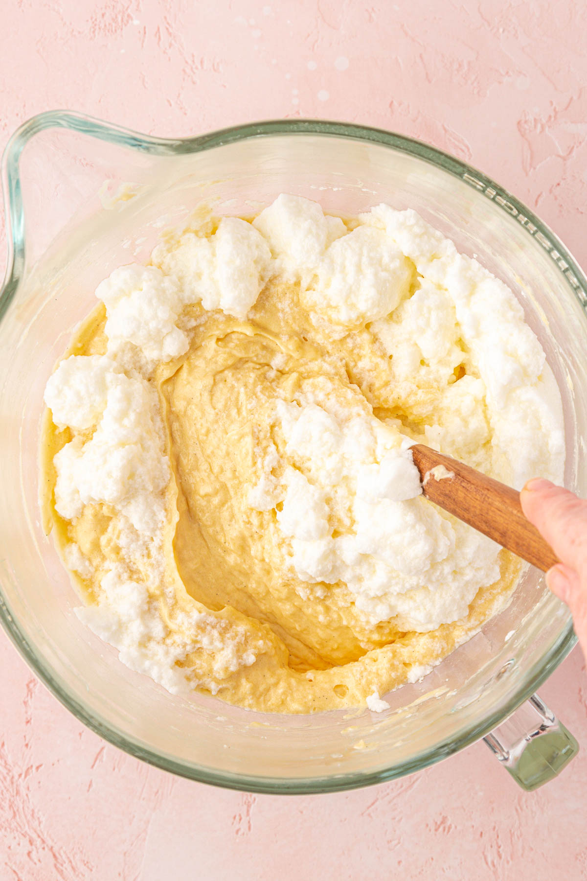 Stiff egg whites being folded into coconut cake batter.