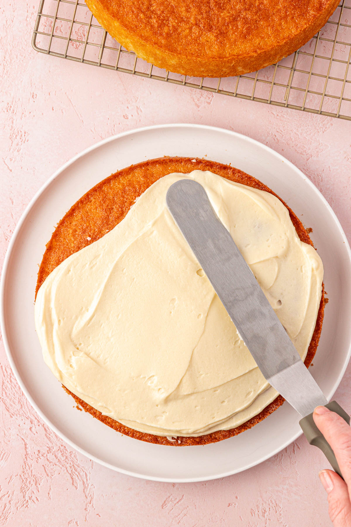 An offset spatula frosting a cake.