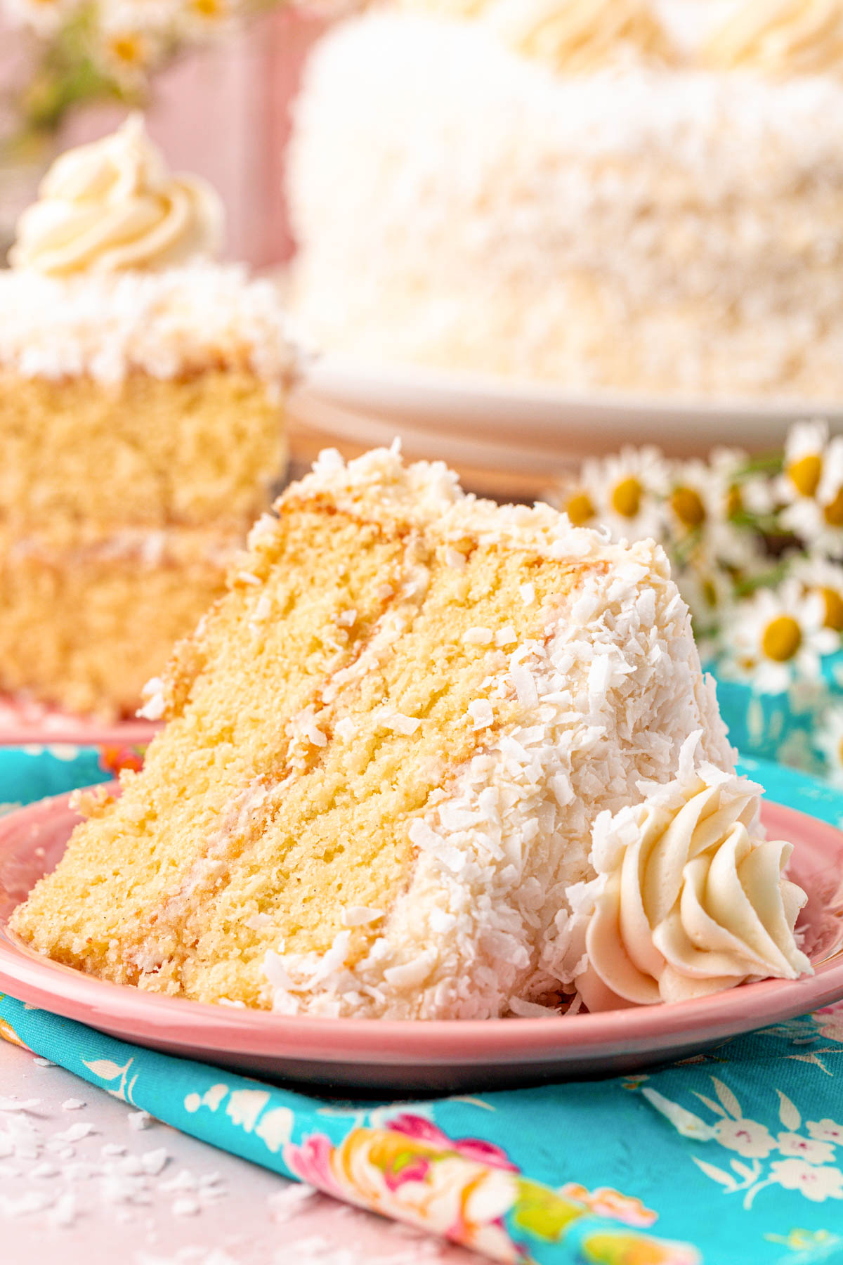 A slice of coconut cake on a pink plate.