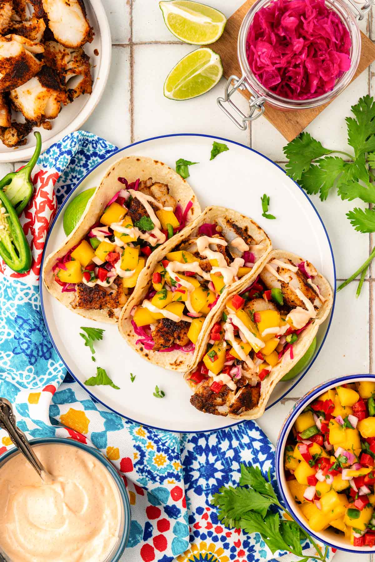 Overhead photo of three fish tacos on a white plate.