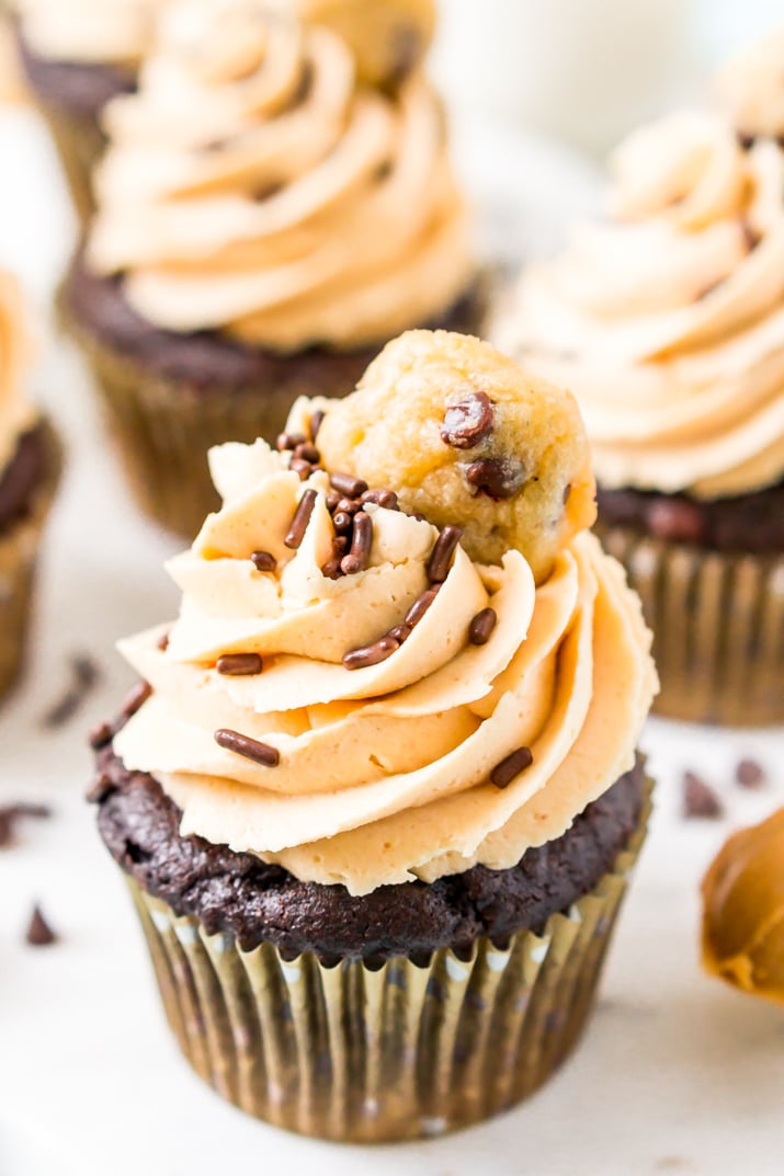 These Cookie Dough Cupcakes are made by stuffing an edible cookie dough into moist chocolate cupcakes and then topping it with a velvety peanut butter frosting, sprinkles, and a mini chocolate chip cookie!