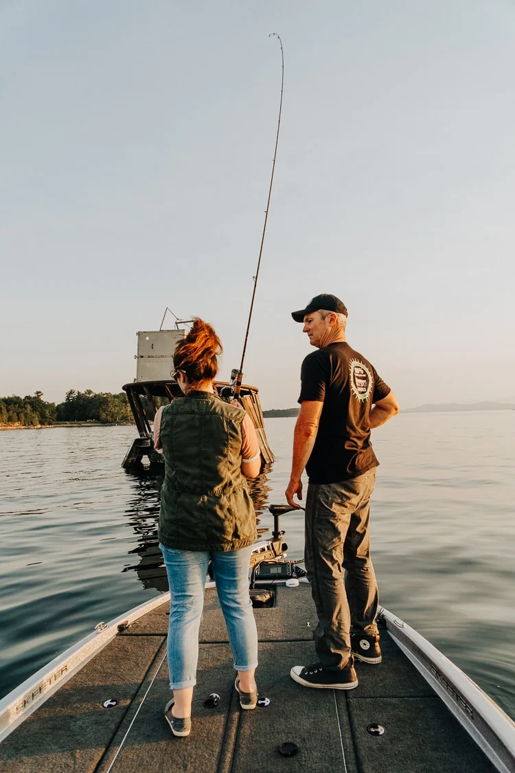 casting a fishing rod, standing on a boat with a guide.