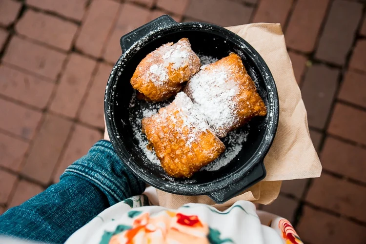 Beignets with powdered sugar in a pan.