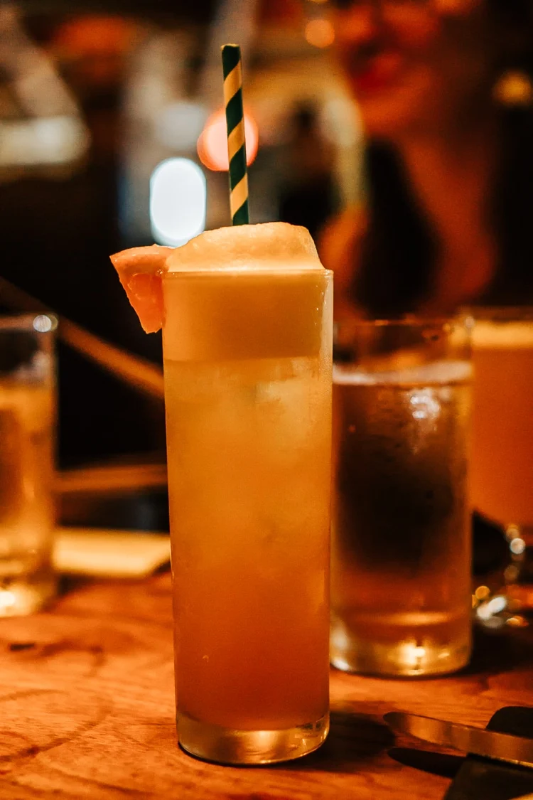 Drink in a tall glass with ice and an orange slice.
