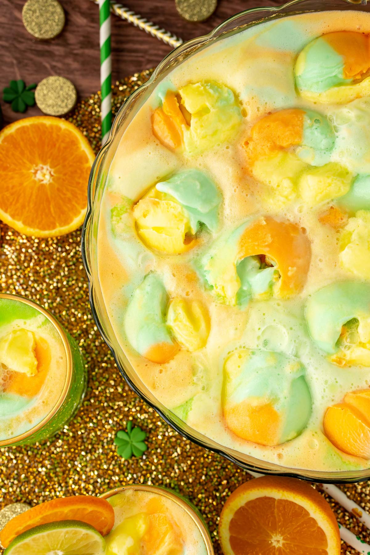 Overhead photo of a punch bowl filled with St. Patrick's Day punch topped with rainbow sherbet.