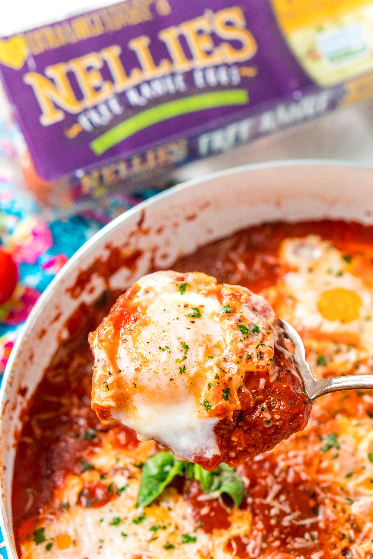 Poached egg being lifted out of Eggs In Purgatory with a serving spoon.