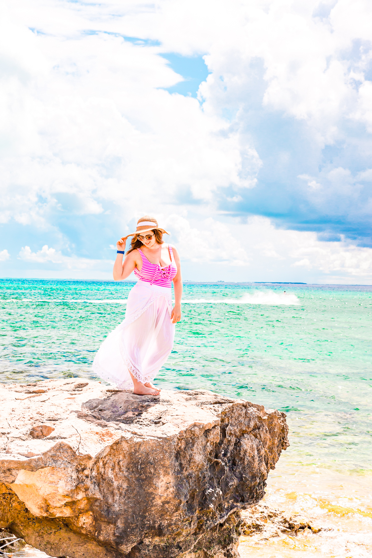 Woman standing on a small cliff over turquoise waters in Grand Turk Cruise Port.