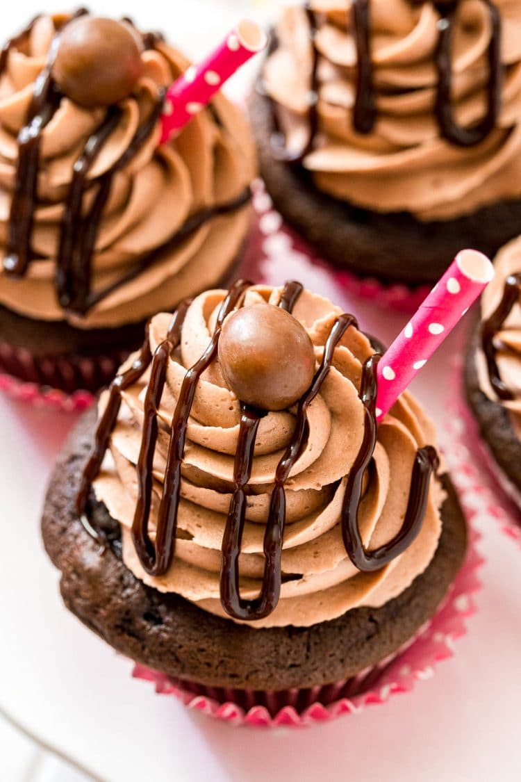 Close up angled photo of chocolate cupcakes on a cake stand.