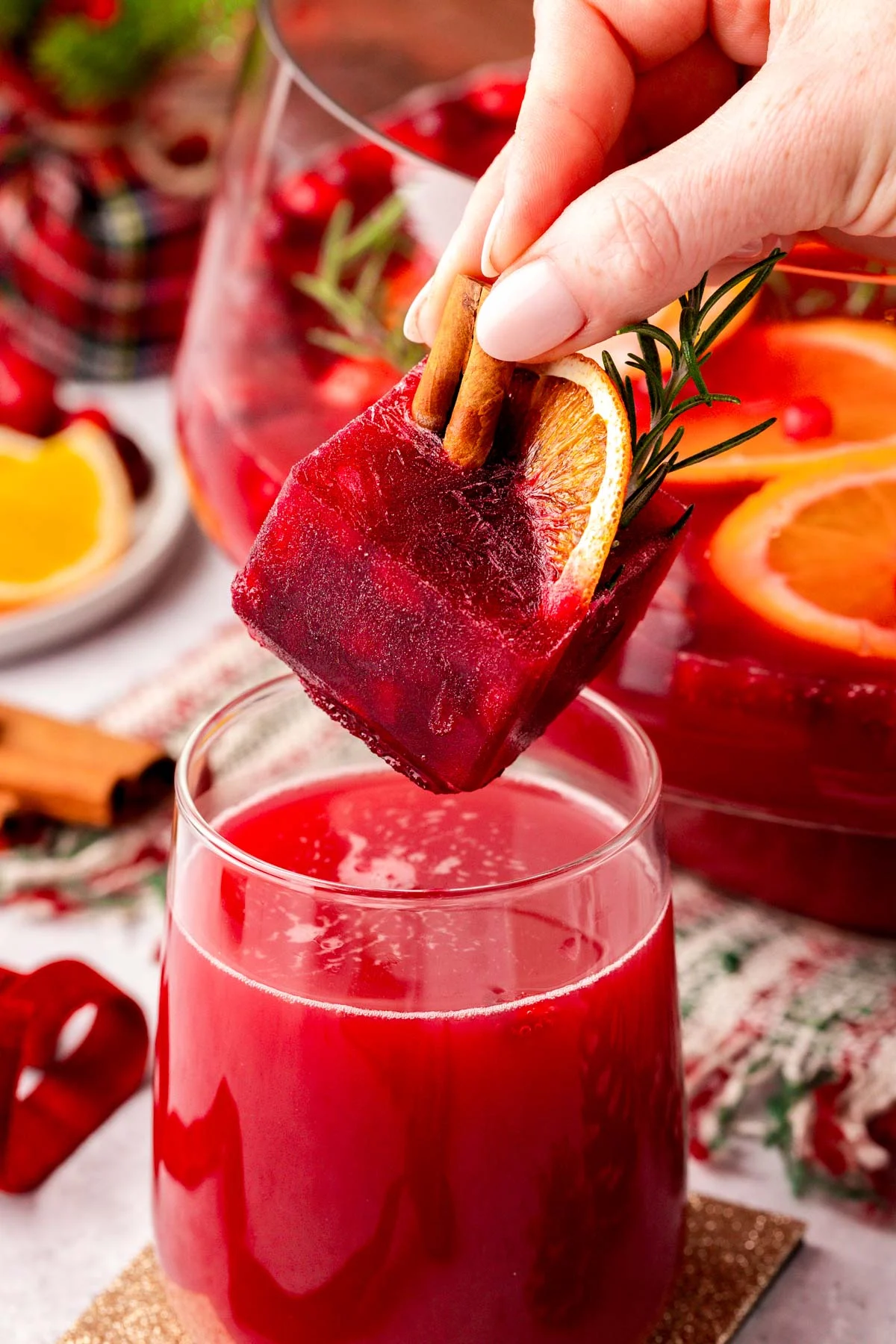 A festive christmas ice cube being added to a glass of Christmas punch!
