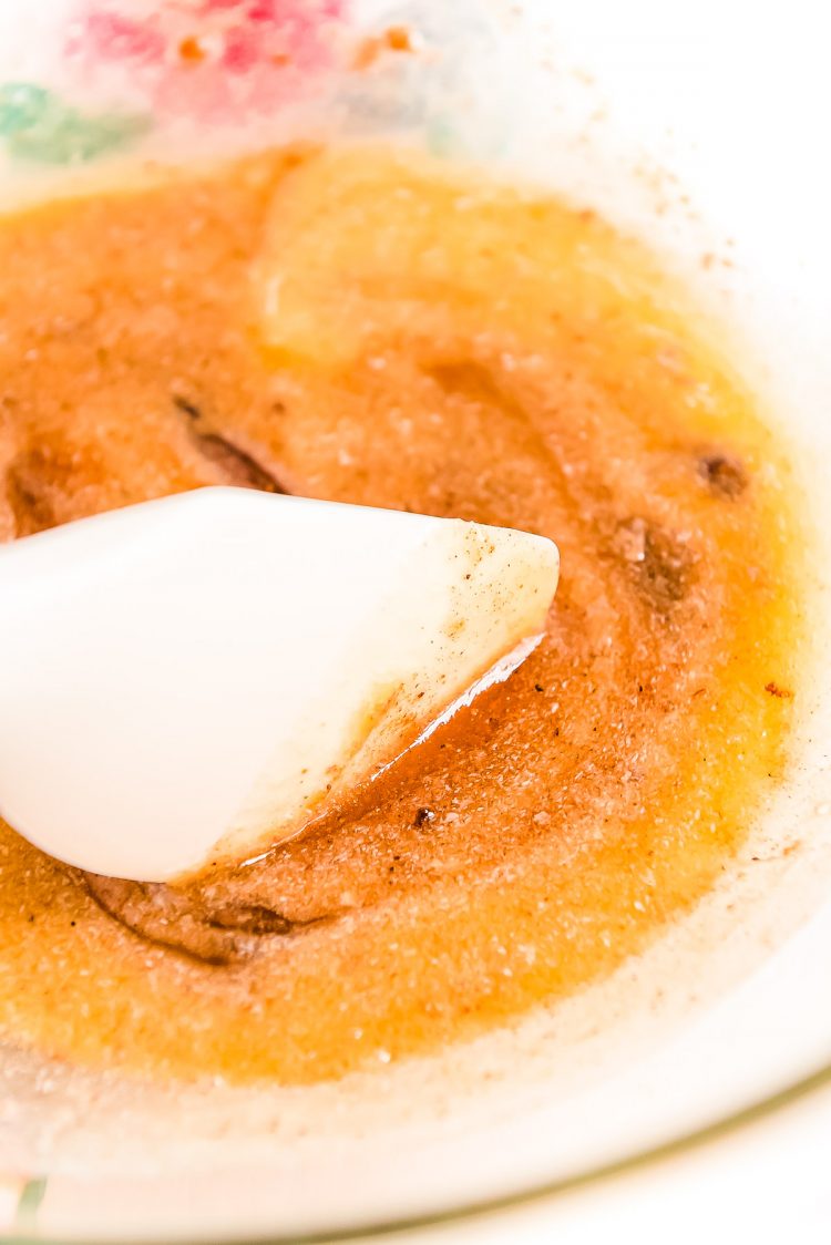 Melted butter and spices being stirred together in a glass bowl.