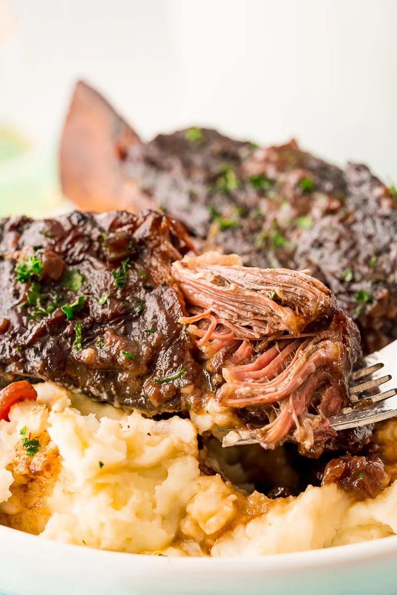A fork taking a bite out of a beef short rib.