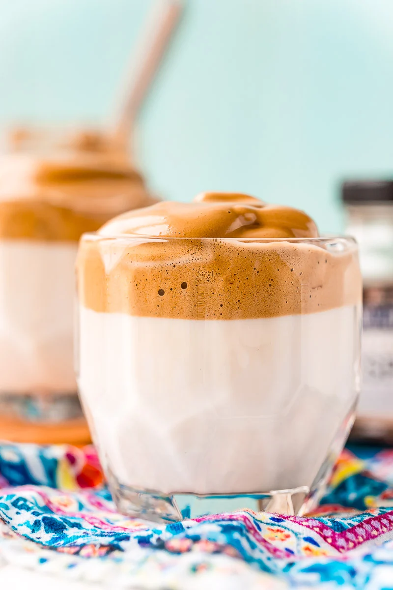 Glass of whipped coffee on a blue patterned napkin.