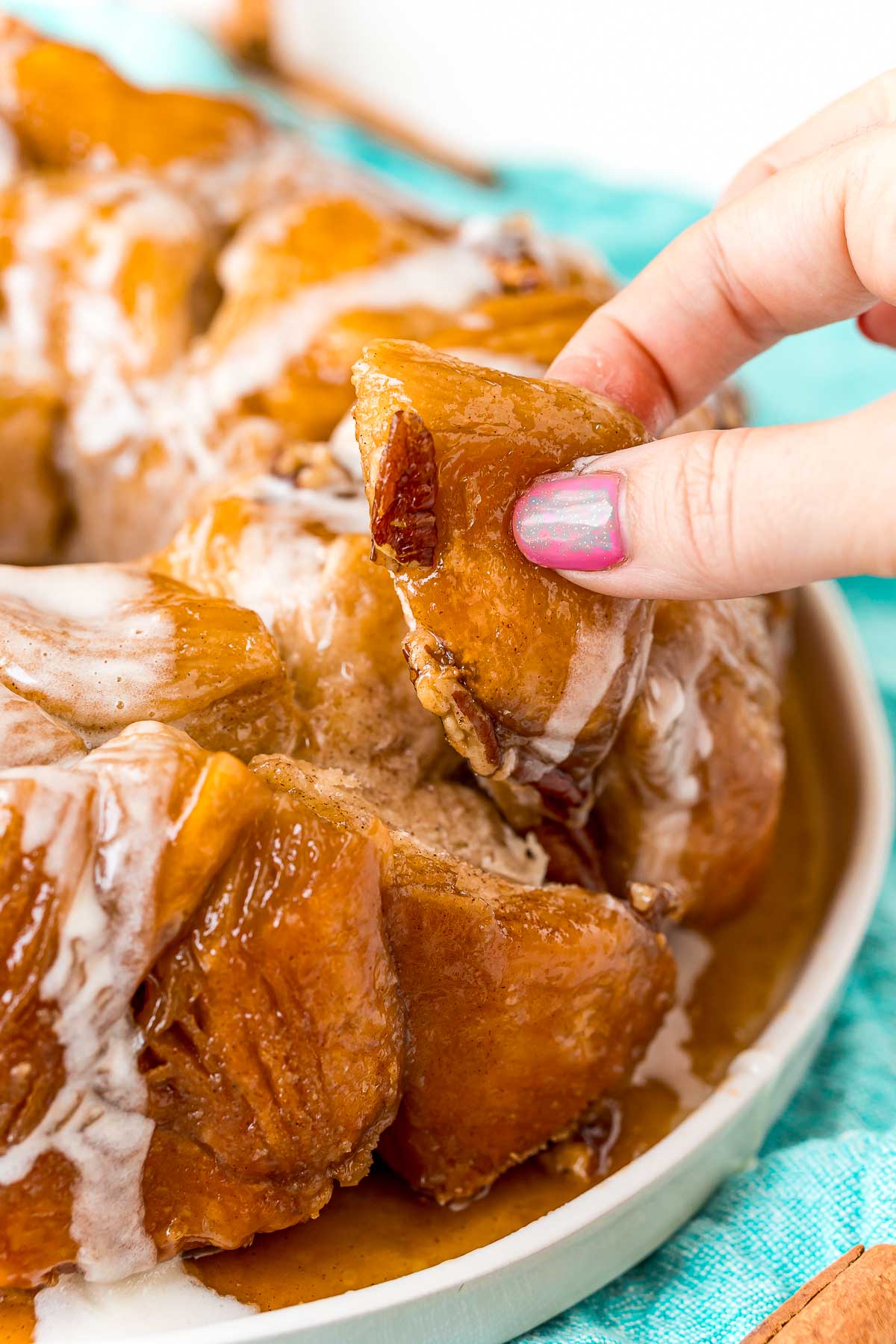 A woman's fingers pulling a piece of monkey bread away from the rest of the bread.