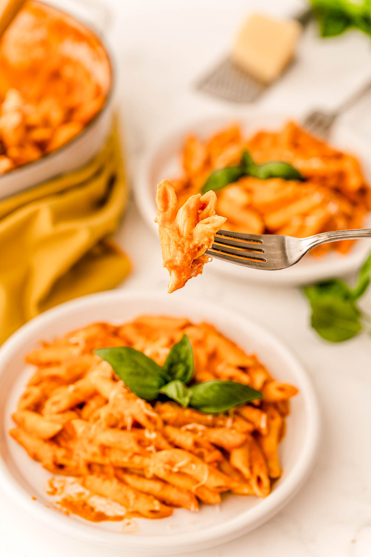 A fork with penne alla vodka being lifted towards the camera.