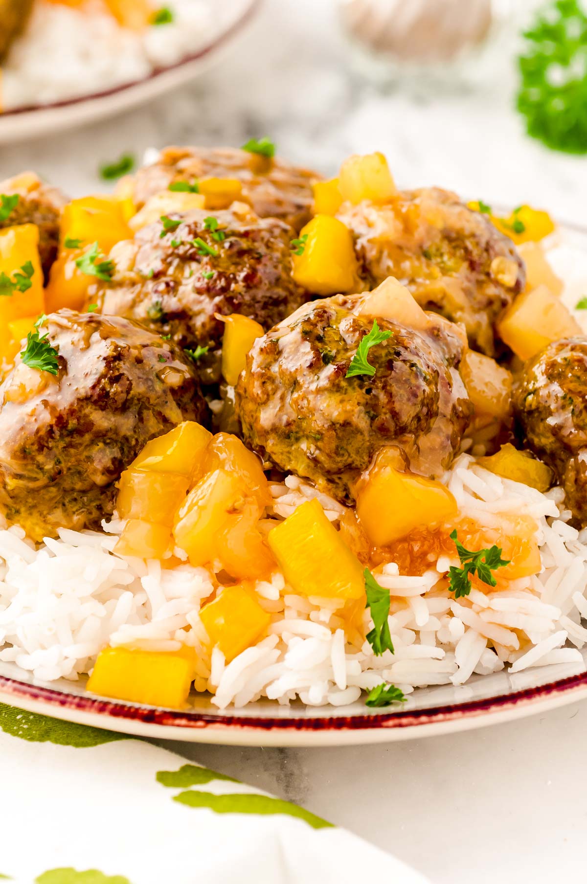 Close up photo of sweet and sour meatballs on a bed of white rice with pineapple.