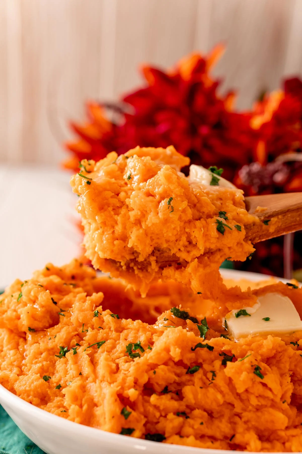 Close up photo of a wooden spoon scooping mashed sweet potato out of a bowl.
