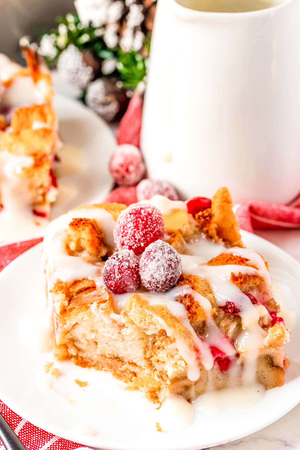 Close up photo of a slice of bread pudding on a white plate with a bite taken out of it.