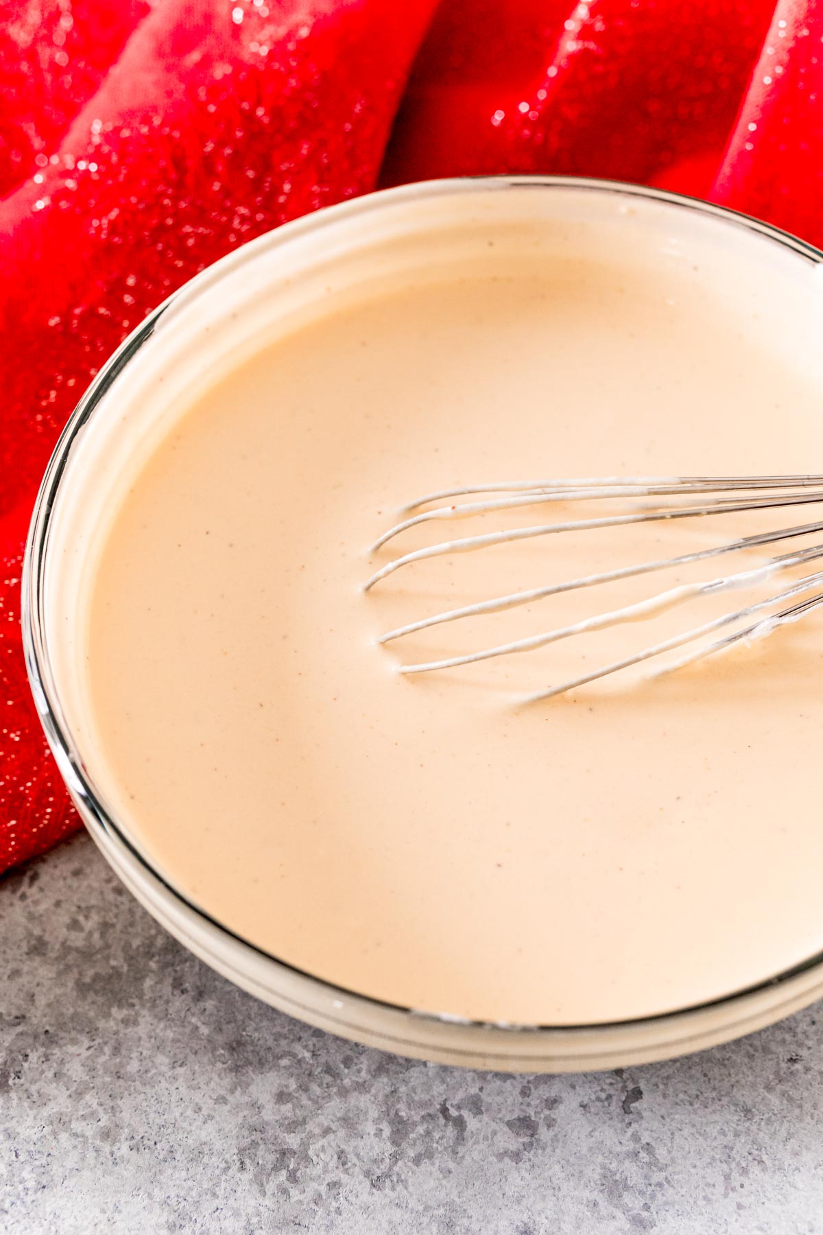 A glass mixing bowl with pudding shot mixture being whisked in it.