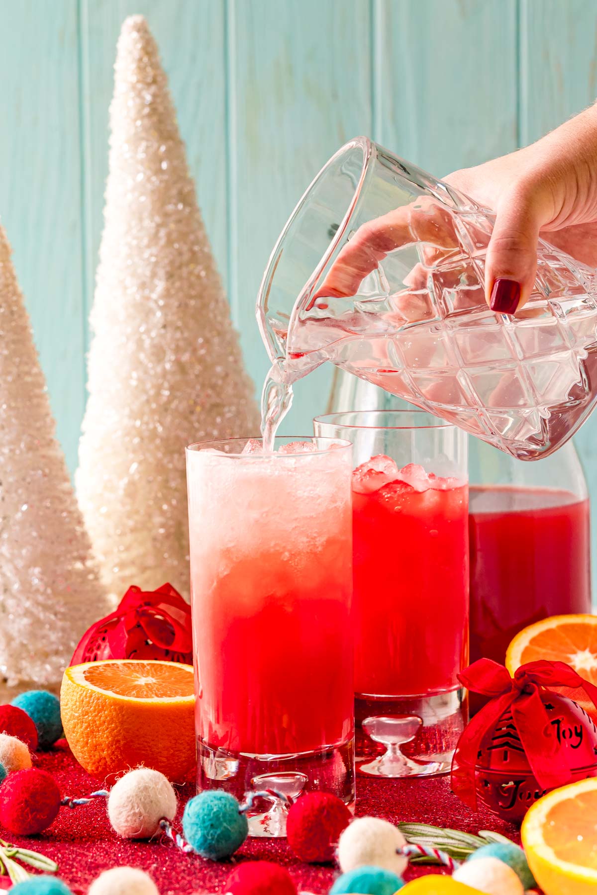 lemon-lime soda being poured into a glass filled with ice and red holiday punch.