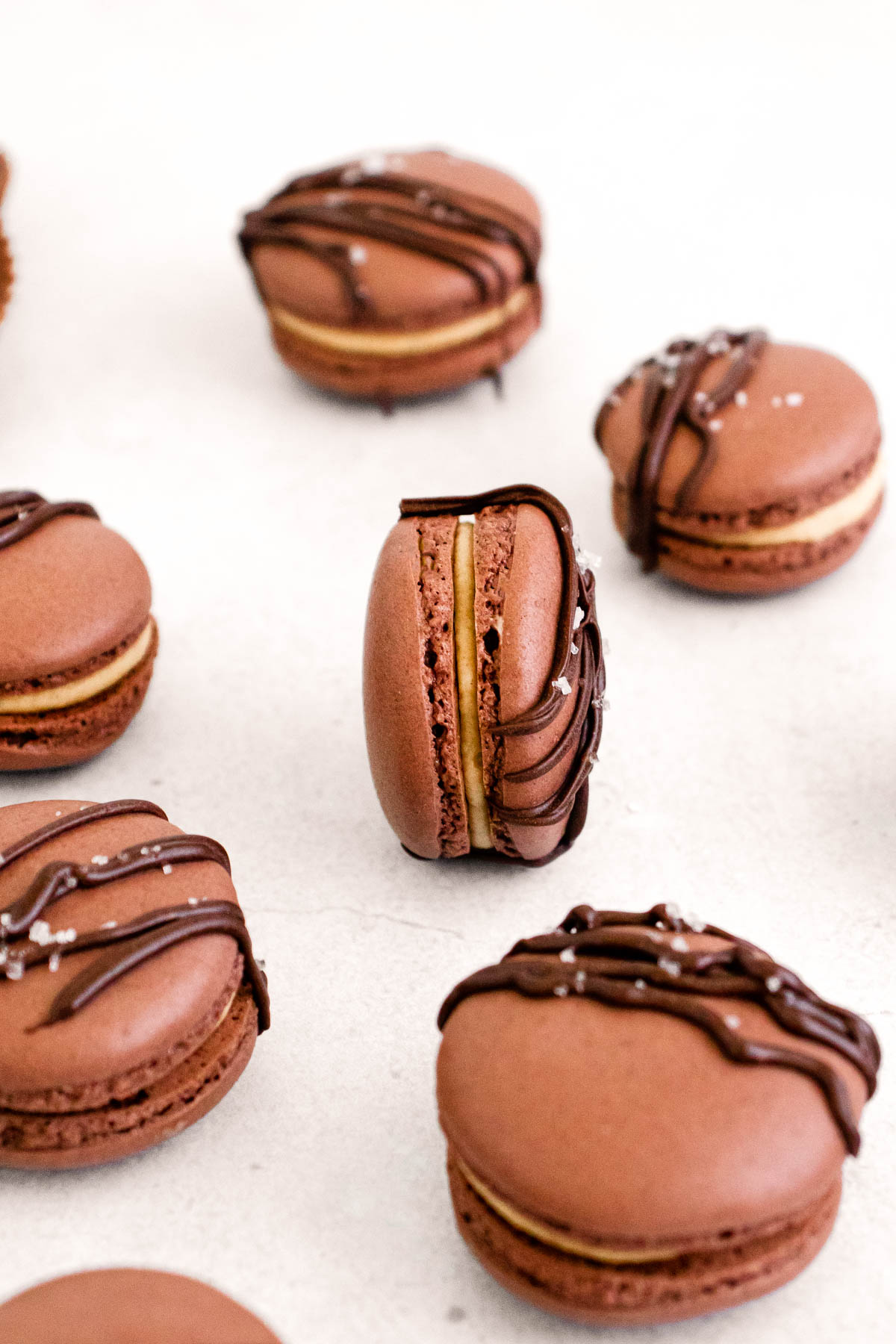 Close up of of peanut butter chocolate macarons on a white counter.