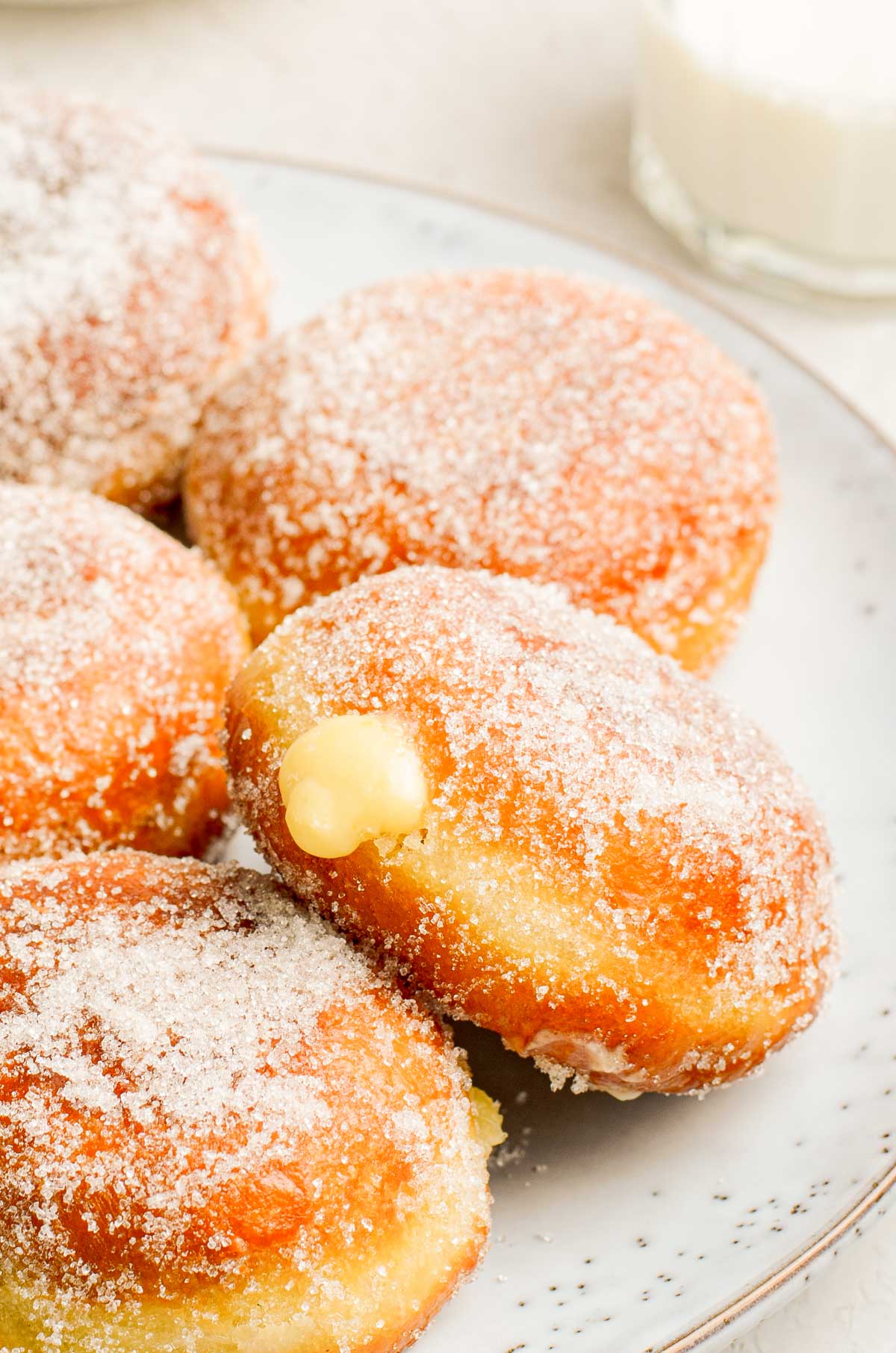 Close up photo of brioche donuts filled with vanilla pastry cream on a plate.