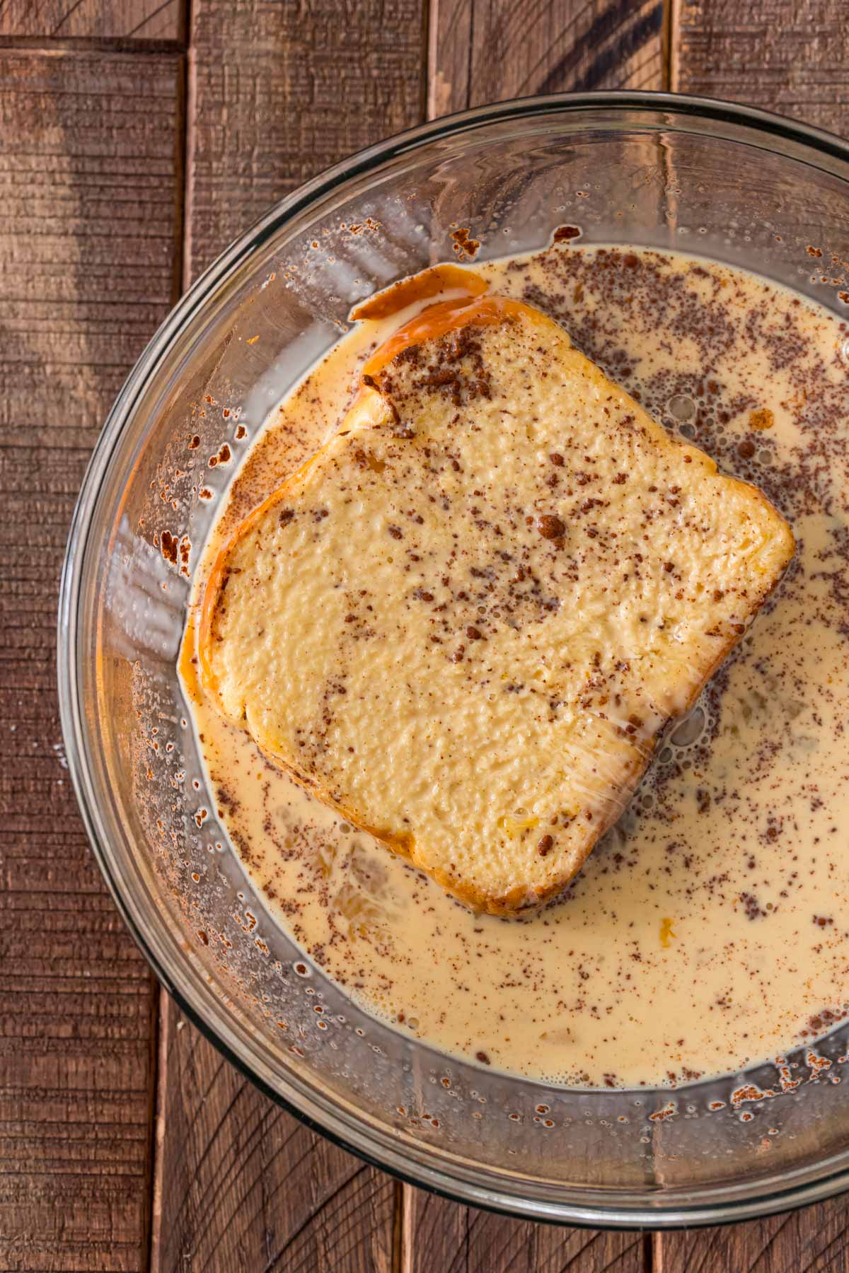 Overhead photo of French toast being dipped in a egg wash.