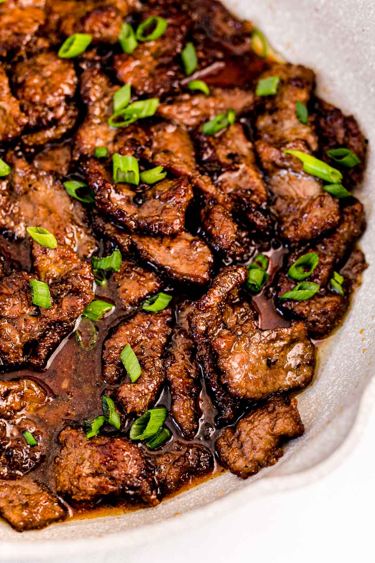 Close up photo of Mongolian beef in a pan garnished with scallions.