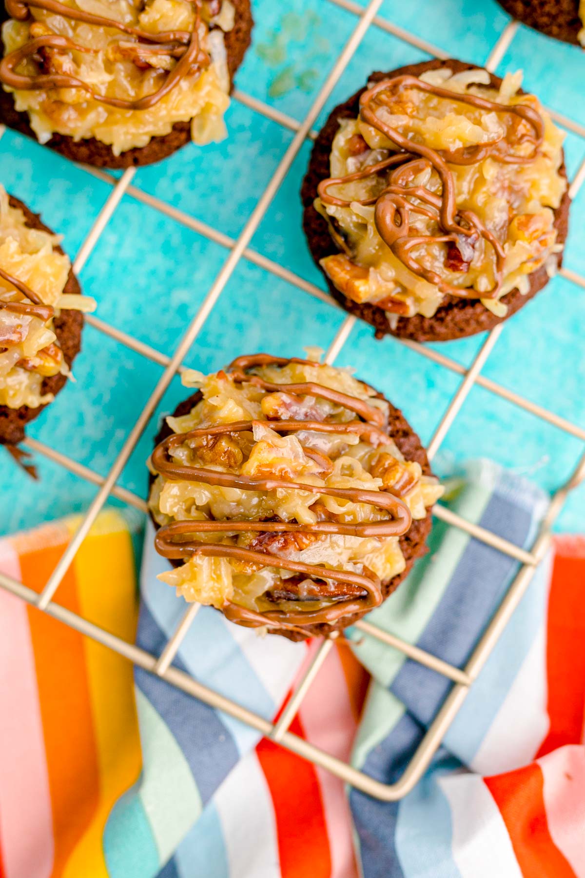 Overhead photo of German chocolate cookies on a cooling rack on a blue table.