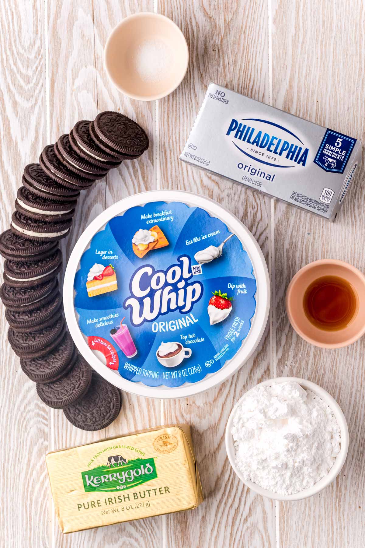 Overhead photo of ingredients to make Oreo no bake cheesecake on a white washed wood surface.