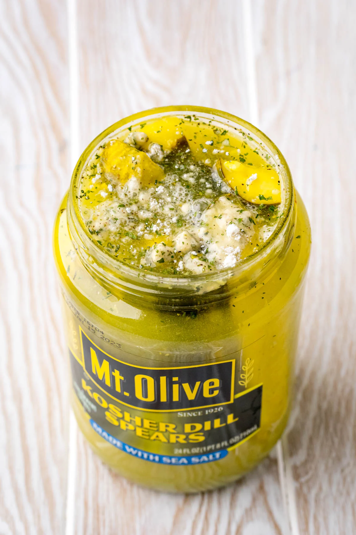 Close up photo of a jar of pickles with ranch seasoning in it.